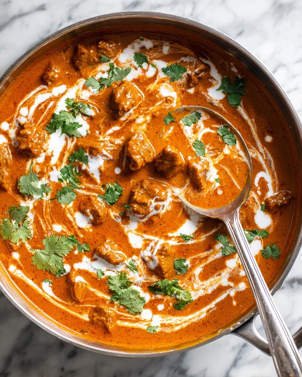 A white bowl filled with a base layer of white rice, topped with a thick orange-yellow chickpea curry sauce with visible chickpeas and small chunks of soft tofu or paneer. The curry is garnished with green cilantro leaves and drizzled lightly with white cream. A folded piece of naan bread with black sesame seeds rests on the side of the bowl, and a bronze spoon is partially dipped into the curry. The bowl is placed on a white marbled textured surface with a second whole naan to the side. photo taken with an iphone --ar 4:5 --v 7
