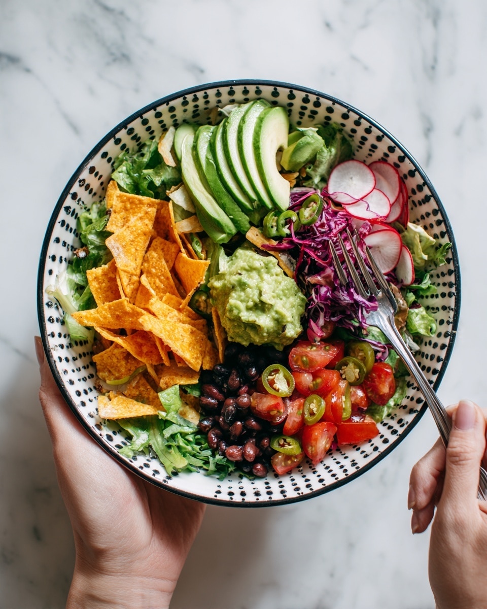 The image shows a colorful salad in a white bowl with black dots around the rim, placed on a white marbled surface. The bottom layer is mixed green leafy vegetables, topped with chopped tomatoes, black beans, sliced radishes, and thin strips of crispy tortilla chips. There are slices of red cabbage and jalapeño peppers scattered across the bowl. On top sits a neat row of bright green avocado slices, and a dollop of creamy green guacamole is placed near the center. A woman's hand holds the bowl, and another woman's hand holds a fork poised over the salad. Photo taken with an iphone --ar 4:5 --v 7