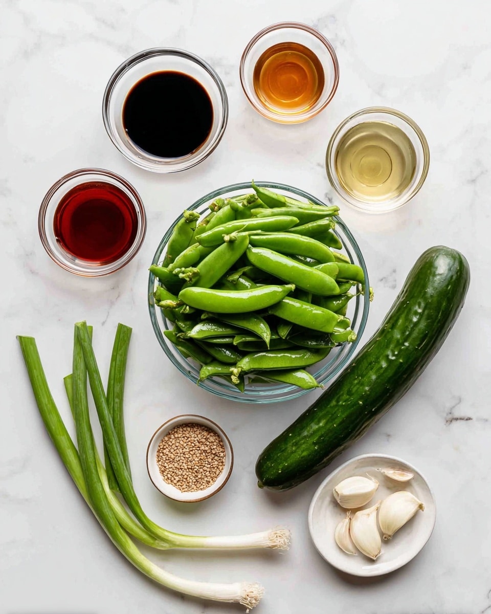 A clear glass bowl filled with bright green snap peas sits in the center on a white marbled surface. To its right, a long, dark green cucumber lays flat. Surrounding these are several small clear glass bowls containing different sauces and ingredients: a dark soy-like sauce, a light golden liquid, clear vinegar, and a reddish chili oil. Below these bowls is a small white dish with brown sesame seeds. On the left side, three green onions run parallel, and above them, three peeled garlic cloves rest on the white marbled surface. The whole composition is clean and bright with a focus on fresh, green ingredients. photo taken with an iphone --ar 4:5 --v 7