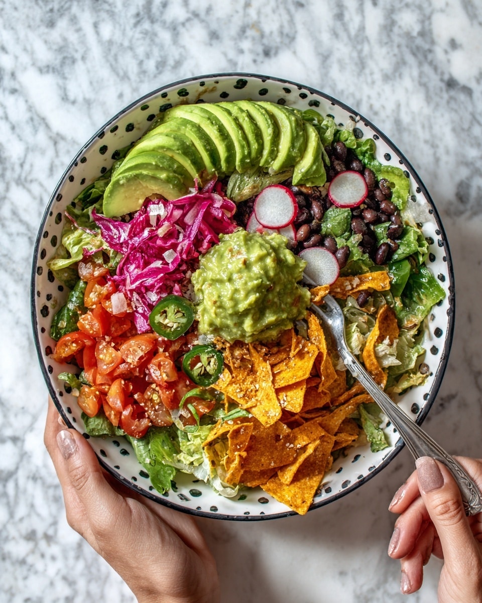 A white bowl with black dots is filled with a colorful salad. The bottom layer is green lettuce. On top, there are sliced red cherry tomatoes, thin round radish slices, bright purple shredded cabbage, and small green leaves. There are also thin beige strips that look like tortilla strips, small chunks of red tomato, and sliced green jalapeños. A sliced avocado fan is placed on one side, and a light green creamy guacamole dollop sits near the center. A woman's hands hold the bowl and a fork with a cream handle, ready to eat. The bowl rests on a white marbled surface with a blue and white striped cloth under the woman's right hand. Nearby, there are small glass bowls with green and red sauces, and a small white plate with lime wedges. Photo taken with an iphone --ar 4:5 --v 7