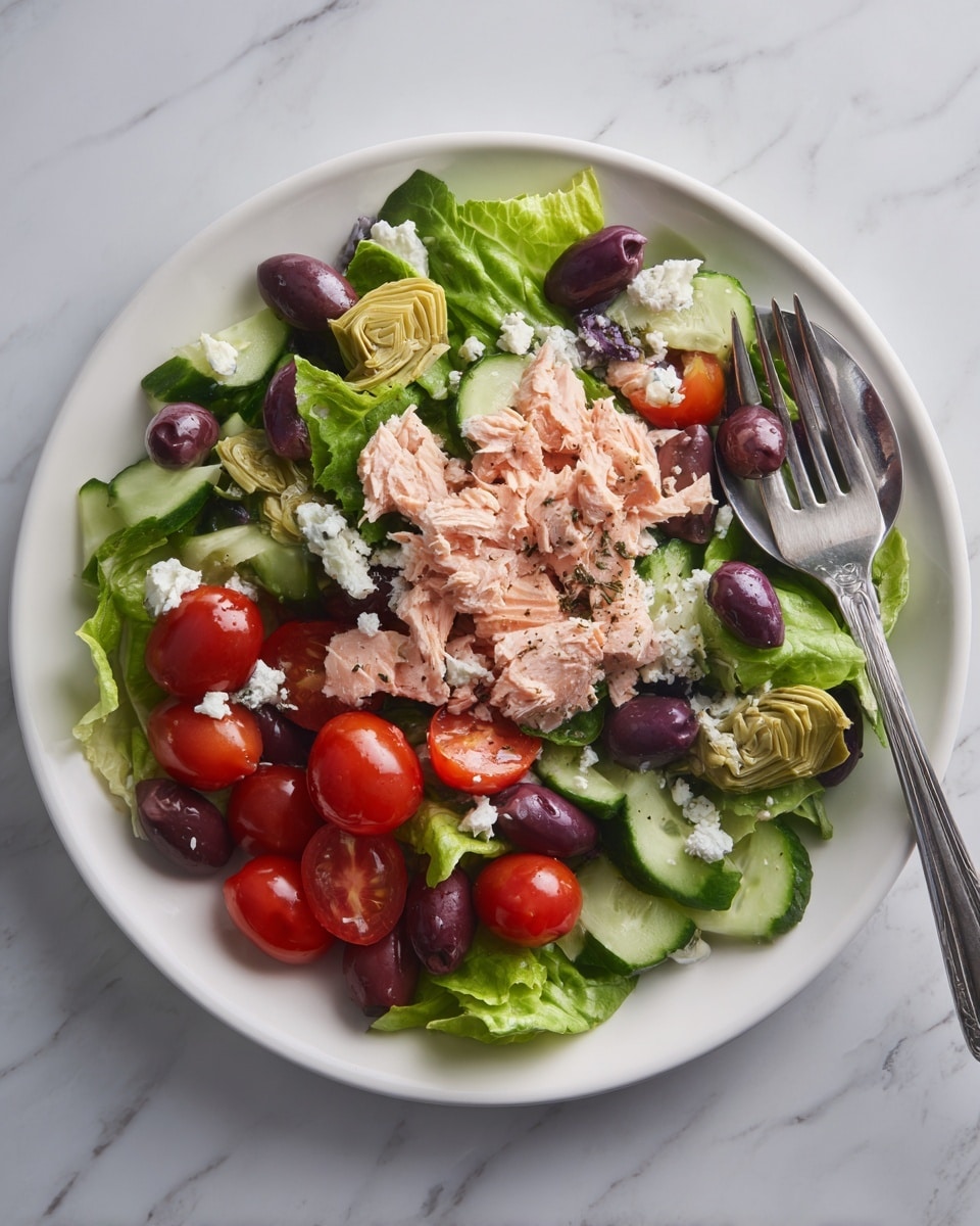 A white plate holds a fresh layered salad starting with a base of bright green leafy lettuce. On top of the lettuce, there are thick pieces of light pink cooked salmon, some decorated with small white feta cheese crumbles. Around the salmon are sliced green cucumbers with a fresh, crisp texture, whole shiny black olives, and several shiny red cherry tomatoes. On the side of the plate, pale yellow artichoke hearts add extra texture, and a silver fork rests against the plate edge. The plate is set on a white marbled surface. photo taken with an iphone --ar 4:5 --v 7